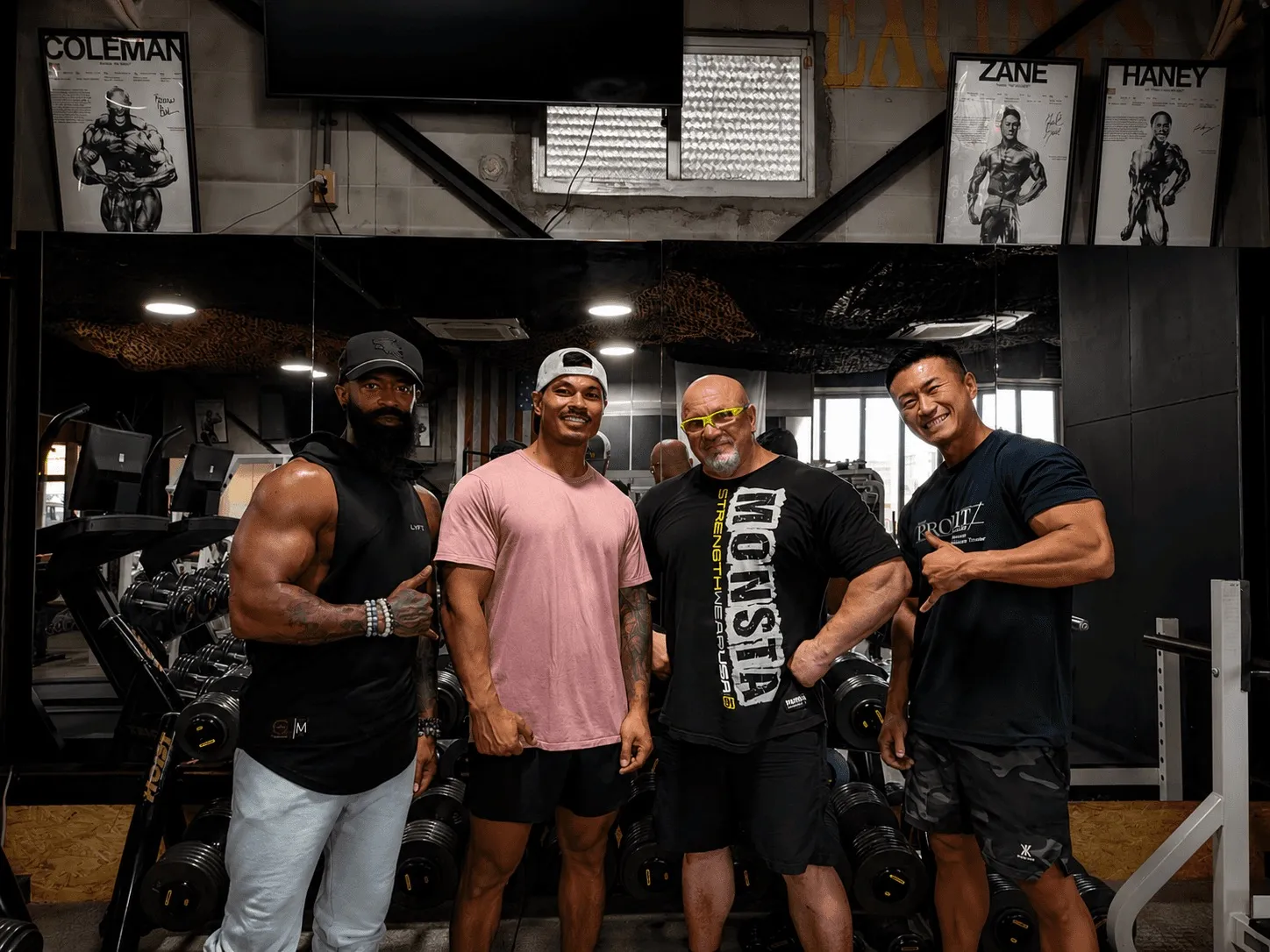 Four Iron Shogun members standing together in front of the dumbbell racks